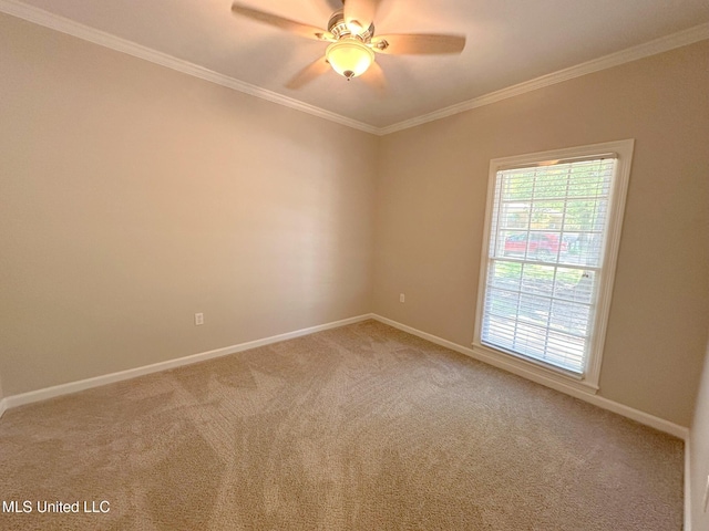 carpeted spare room with ornamental molding, baseboards, and a ceiling fan