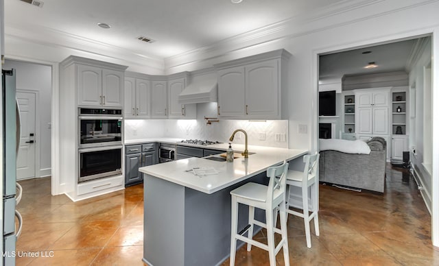 1025 Monet Cv, Brandon, MS 39047 - kitchen featuring stainless steel appliances, a peninsula, gray cabinets, premium range hood, and crown molding