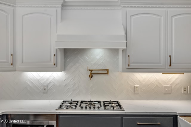 1025 Monet Cv, Brandon, MS 39047 - kitchen with stainless steel gas cooktop, tasteful backsplash, light stone countertops, and white cabinets