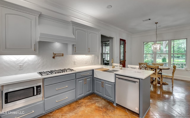 1025 Monet Cv, Brandon, MS 39047 - kitchen featuring appliances with stainless steel finishes, gray cabinetry, a sink, a peninsula, and backsplash