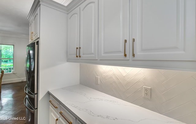 1025 Monet Cv, Brandon, MS 39047 - kitchen featuring freestanding refrigerator, decorative backsplash, light stone counters, white cabinetry, and ornamental molding