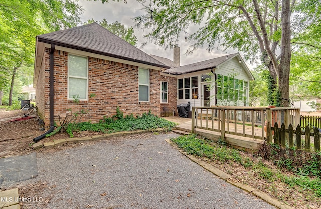 1025 Monet Cv, Brandon, MS 39047 - back of house with a wooden deck, a shingled roof, brick siding, a chimney, and a sunroom