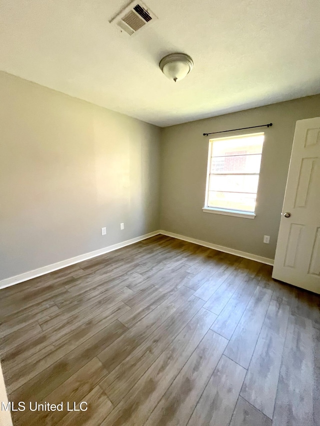 spare room with dark wood-type flooring and baseboards