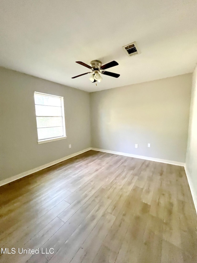 spare room with a ceiling fan, wood finished floors, and baseboards
