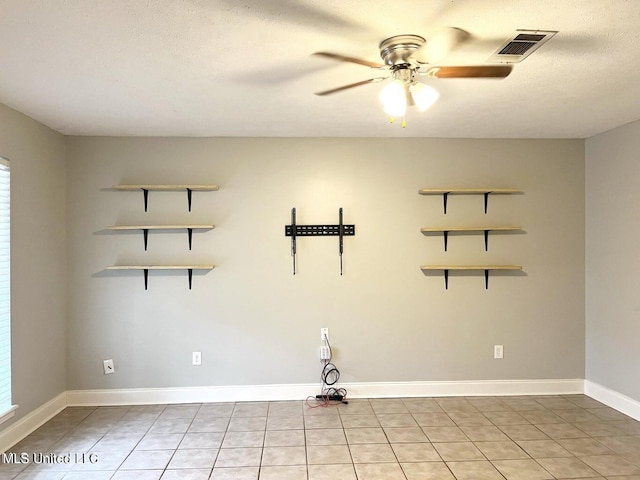empty room with ceiling fan, light tile patterned floors, baseboards, and a textured ceiling