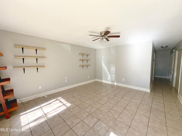 empty room featuring light tile patterned floors, ceiling fan, and baseboards