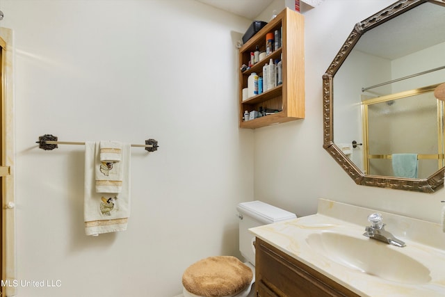 bathroom featuring toilet, vanity, and a shower with door