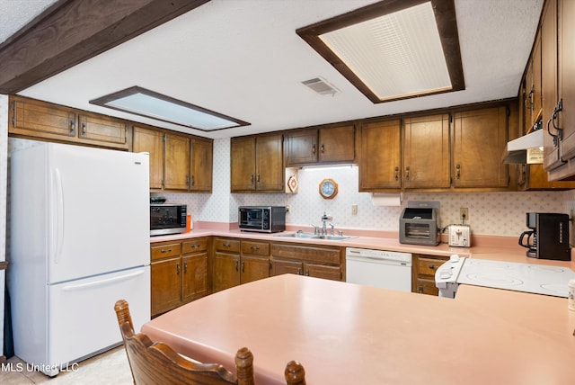 kitchen with white appliances, sink, kitchen peninsula, and ventilation hood