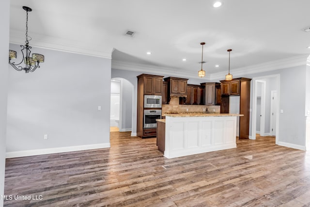 709 Champagne Dr, Biloxi, MS 39532 - kitchen featuring appliances with stainless steel finishes, arched walkways, light wood-style flooring, tasteful backsplash, and crown molding