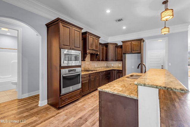 709 Champagne Dr, Biloxi, MS 39532 - kitchen featuring stainless steel appliances, arched walkways, backsplash, light stone countertops, and decorative light fixtures