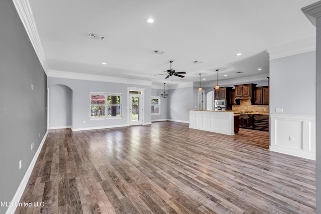709 Champagne Dr, Biloxi, MS 39532 - unfurnished living room featuring a ceiling fan, arched walkways, wood finished floors, recessed lighting, and ornamental molding