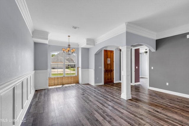 709 Champagne Dr, Biloxi, MS 39532 - empty room with ornamental molding, a chandelier, dark wood-style flooring, arched walkways, and wainscoting
