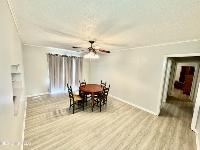 dining room featuring light wood-type flooring, crown molding, baseboards, and ceiling fan