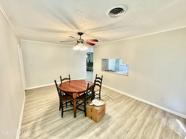 dining room with baseboards, crown molding, visible vents, and wood finished floors