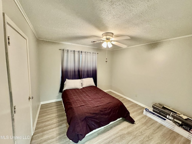 bedroom featuring crown molding, ceiling fan, a textured ceiling, wood finished floors, and baseboards