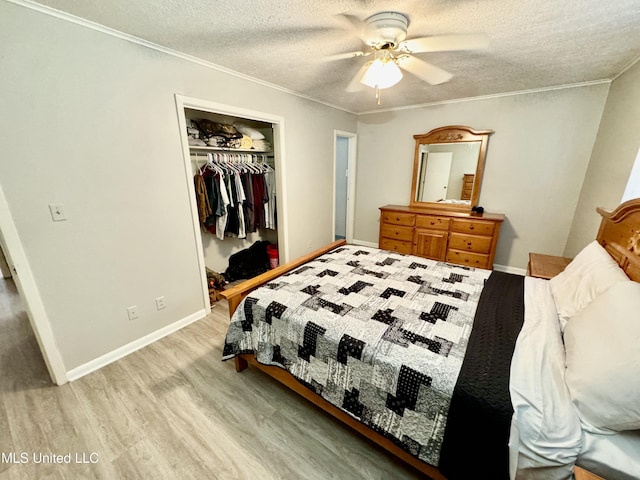 bedroom featuring light wood finished floors, baseboards, ornamental molding, a textured ceiling, and a closet