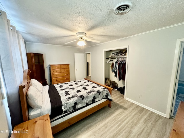 bedroom with visible vents, ornamental molding, wood finished floors, a textured ceiling, and a closet