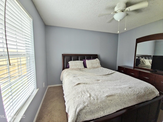 bedroom with a textured ceiling, baseboards, a ceiling fan, and carpet floors