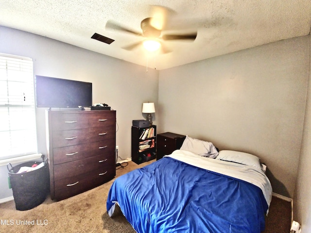bedroom with carpet flooring, ceiling fan, and a textured ceiling