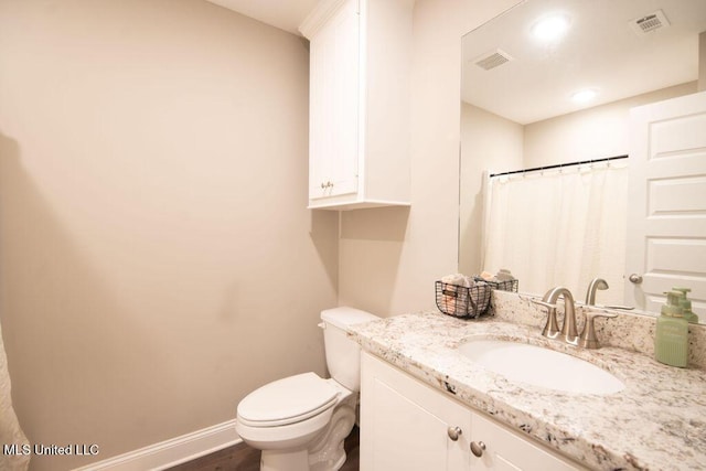 bathroom with toilet, visible vents, wood finished floors, and vanity