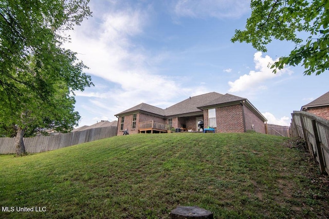 rear view of property with brick siding, a fenced backyard, and a yard