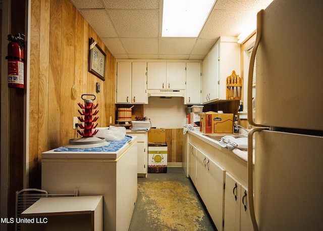 103 Hidden Lake Rd, Flora, MS 39071 - kitchen with freestanding refrigerator, under cabinet range hood, concrete floors, white cabinetry, and a paneled ceiling