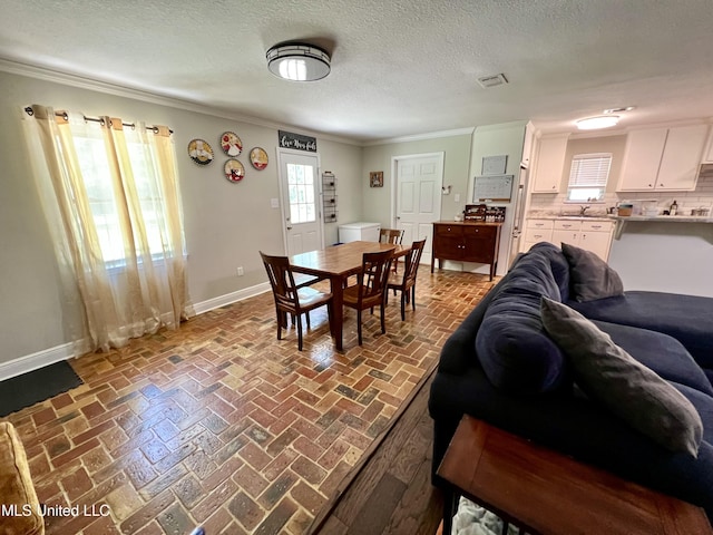 dining space with baseboards, ornamental molding, a textured ceiling, and brick flooring