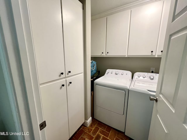 laundry area featuring washing machine and dryer, brick flooring, and cabinet space