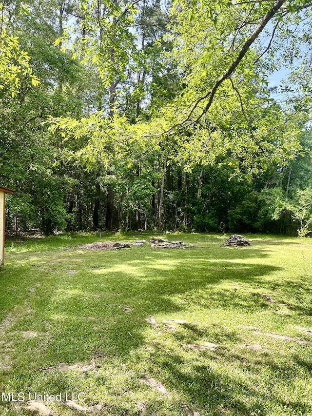 view of grassy yard featuring a view of trees