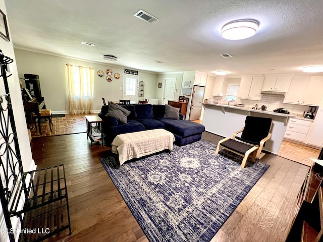 living area featuring light wood-style flooring, a textured ceiling, and baseboards