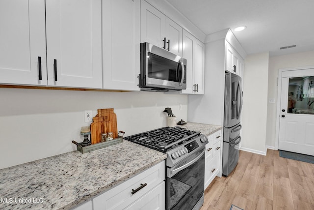 6177 W Sandbourne, Olive Branch, MS 38654 - kitchen featuring visible vents, light stone counters, light wood finished floors, stainless steel appliances, and white cabinetry