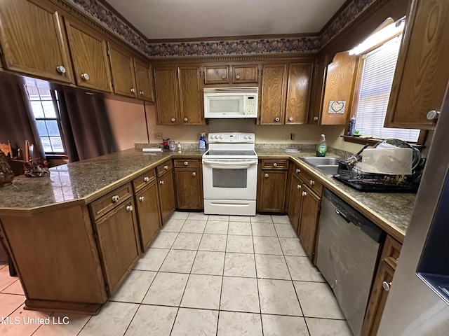 kitchen featuring white appliances, kitchen peninsula, and light tile patterned floors