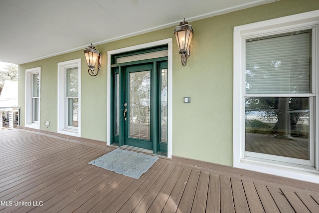 doorway to property with a porch and stucco siding