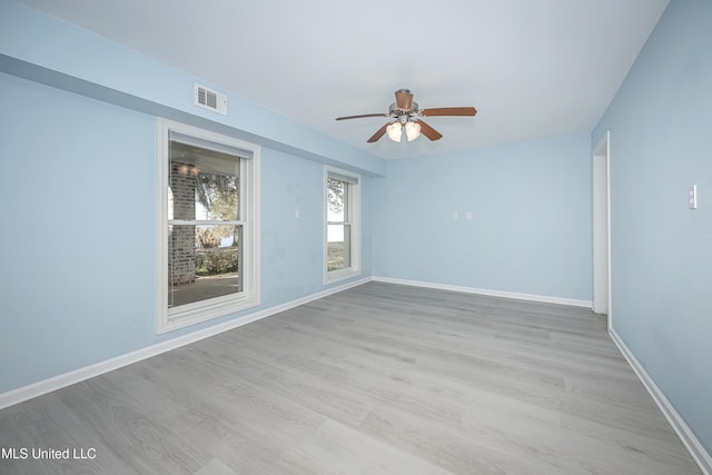 spare room with light wood-style floors, visible vents, ceiling fan, and baseboards