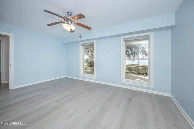 spare room featuring a wealth of natural light, visible vents, baseboards, and wood finished floors