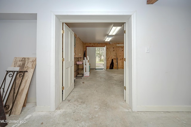 corridor featuring baseboards and concrete flooring