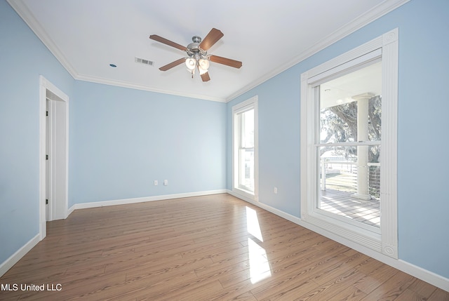 spare room with baseboards, visible vents, crown molding, and wood finished floors