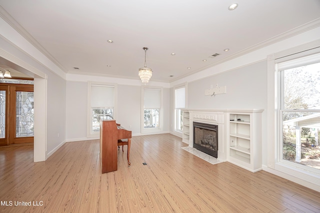 interior space with visible vents, light wood-style flooring, a fireplace with flush hearth, crown molding, and recessed lighting