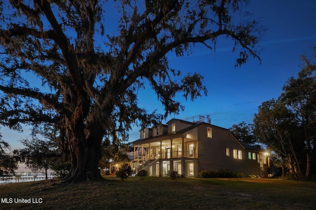 view of property exterior featuring covered porch, a yard, stairway, and a balcony