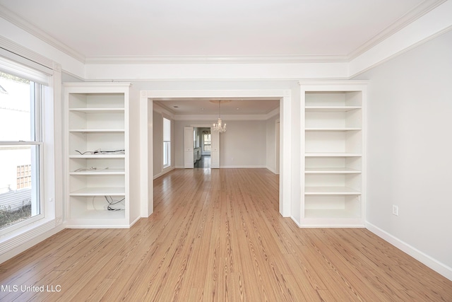 unfurnished room featuring ornamental molding, light wood-type flooring, and an inviting chandelier