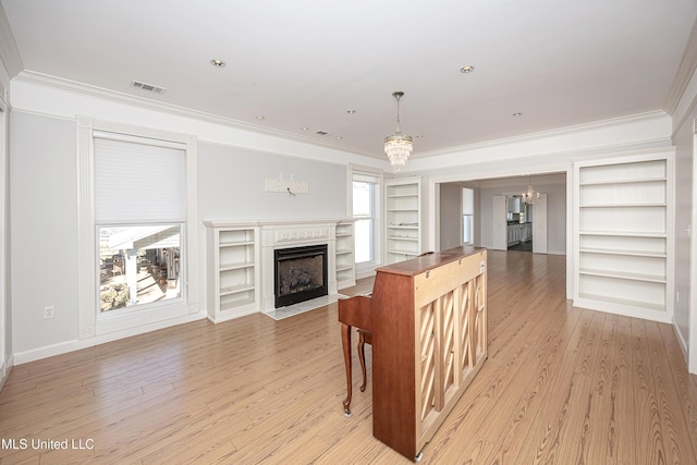 living room with built in shelves, light wood-type flooring, a fireplace with flush hearth, and crown molding