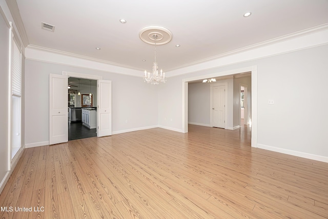 empty room with light wood-style flooring, visible vents, baseboards, and ornamental molding