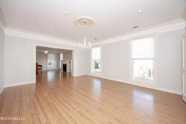 unfurnished living room with light wood-style floors, visible vents, a fireplace, and ornamental molding