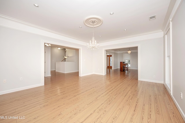 spare room featuring a notable chandelier, visible vents, light wood-style flooring, ornamental molding, and baseboards