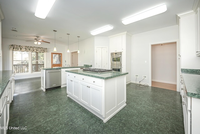 kitchen with dark floors, stainless steel appliances, a peninsula, a kitchen island, and white cabinetry