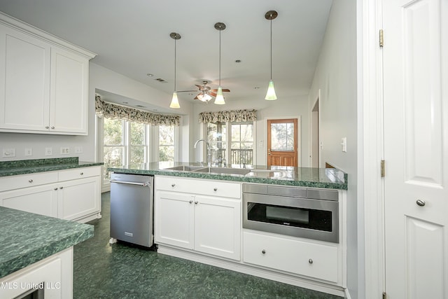 kitchen with dark countertops, a healthy amount of sunlight, white cabinetry, and pendant lighting