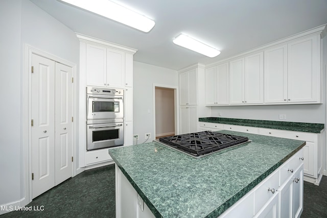 kitchen featuring dark countertops, a kitchen island, appliances with stainless steel finishes, and white cabinets