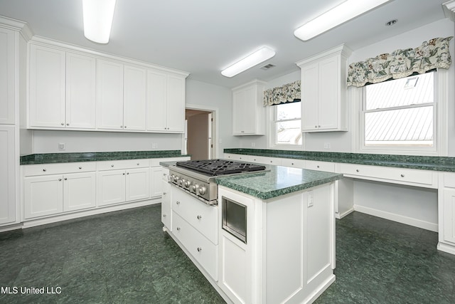 kitchen with visible vents, dark countertops, dark floors, white cabinetry, and stainless steel gas cooktop