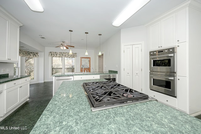 kitchen featuring stainless steel double oven, white cabinets, ceiling fan, and gas stovetop