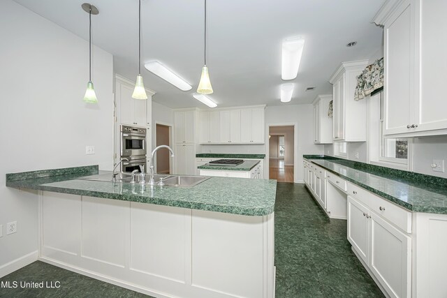 kitchen featuring stainless steel appliances, a peninsula, a sink, white cabinets, and pendant lighting